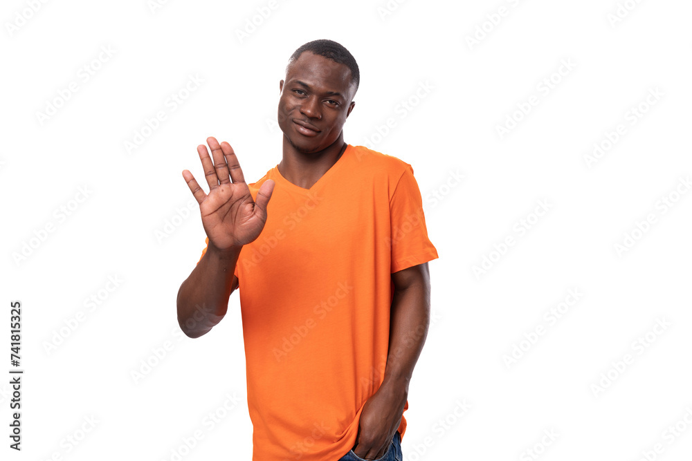 Wall mural young american man dressed in basic orange t-shirt having doubts and suspicion on white background with copy space