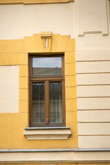 Window with brown frame on light yellow vintage, old building. Architect style classicism concept....