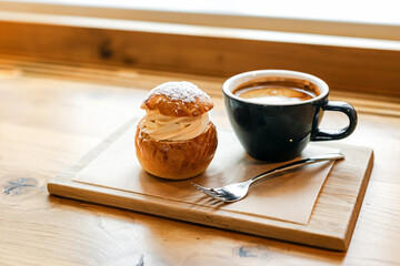 Traditional semla sweet bun with almond paste topped with whipped cream and cup of black coffee