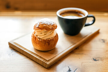 Traditional semla sweet bun with almond paste topped with whipped cream and cup of black coffee - 741822196