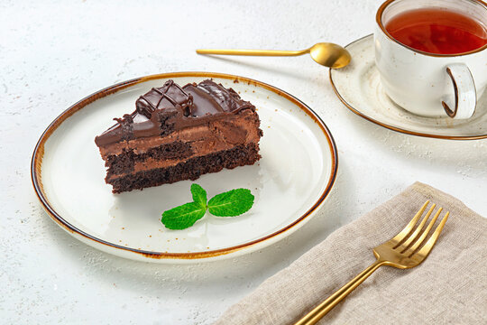 Chocolate cake and tea on a plate with a fork and a spoon