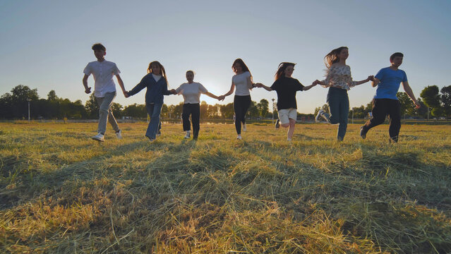 Children running on meadow at sunset.