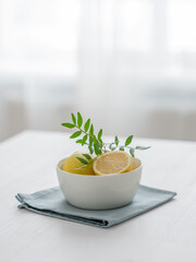 Fresh lemons in a bowl on a white wooden table in front of a window with morning natural light.