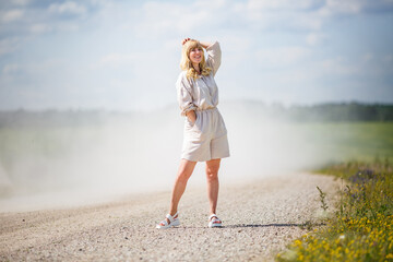 young girl in linen suit posing on gravel country road in the dust