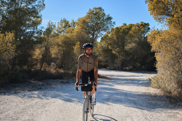Cyclist practicing on gravel road. Fit male cyclist riding a gravel bike on a gravel road, Alicante region of Spain. Beautiful sunny day for cycling. Motivation image of an athlete.