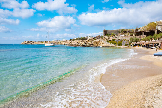 Paraside Beach in Mikonos, Greece, umbrella and luxury beach chairs beds in front of blue ocean. Most famous beach with crystal water and beach music bars.
