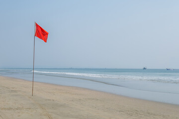 red flag on beach on sea or ocean as a symbol of danger. The sea state is considered dangerous and...