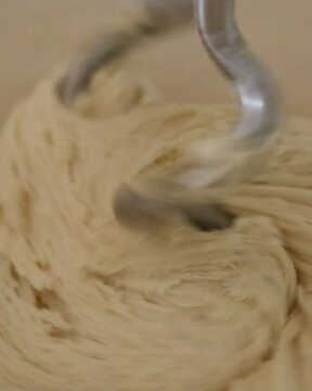 The electric mixer whisks stir the wheat flour dough, close-up.