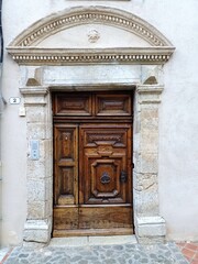 Magnificent ancient stone door with pediment and carved solid wood giving access to a Provencal style mansion or mansion in Provence, in the south of France
