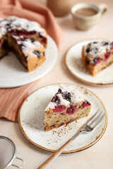 Hazelnut, chocolate and cherry cake. Orange napkin and background. Milk jug and cup of coffee.