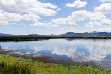 beautiful lagoon landscape with clouds and mountains reflected in it