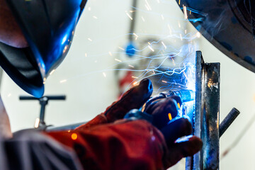 Welder worker welding a pieces of metal in the industrial factory, heavy weld industry concept