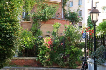 Végétation luxuriante au printemps dans une ruelle pittoresque de la Cité Florale, dans la ville de Paris, ensemble de rues avec de nombreuses plantes vertes devant les maisons (France)