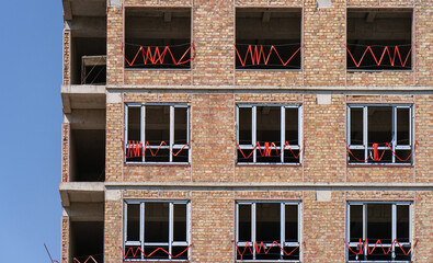Under construction brick multi-story residential building..Installation of new window frames in the...
