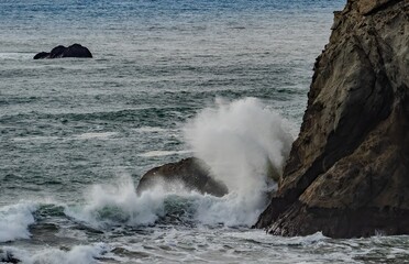 Fototapeta premium A large wave crashing against a large seastack on the Bandon beach on the Oregon coast.