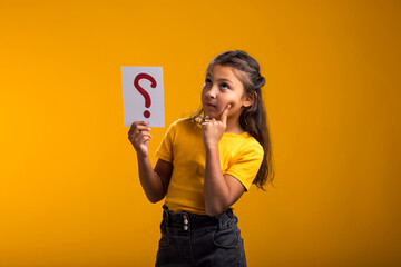 Thoughtful kid girl holding question mark card. Children, idea and knowledge concept