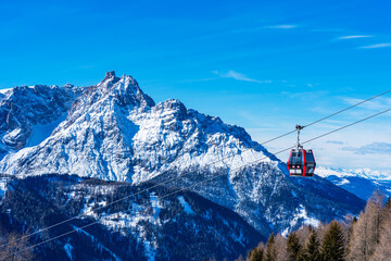 Cable car gondola against blue sky and snow covered Dolomites in Kronplatz, Italy