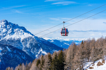Cable car gondola against blue sky and snow covered Dolomites in Kronplatz, Italy
