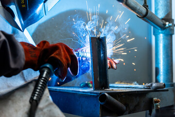 Welder worker welding a pieces of metal in the industrial factory, heavy weld industry concept