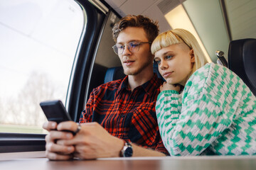 A young traveler couple is traveling by train and buying tickets online.