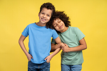 Smiling African American children cute brother and sister wearing stylish colorful clothes, hugging - obrazy, fototapety, plakaty