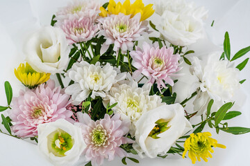 On a light background, a delicate bouquet with chrysanthemums and eustoma.