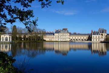 Beautiful Medieval landmark - royal hunting castle Fontainbleau with reflection in water of pond. - 741934587