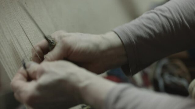 Woman weaving carpets using old methods, close-up