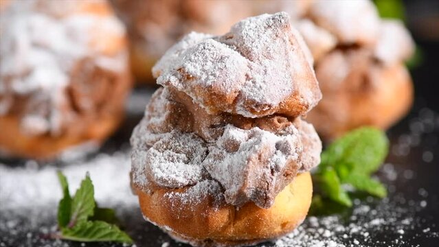 Profiteroles or cream puff with filling,  powdered sugar topping with berries, on black background. Fresh homemade Cream Puffs, cake, tasty French choux puff, ecler, dessert closeup. Pastries