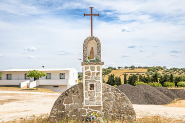 Christian Cross and a chapel with Our Lady and child Jesus on the road leaving Segura, municipality of Idanha-a-Nova, province of Beira Baixa, Castelo Branco, Portugal - 741954998