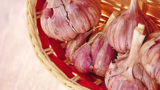 Gyration of old garlic in a straw basket on a wooden table background.