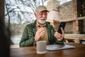 One senior man sit in front of tiny house in day use smart phone