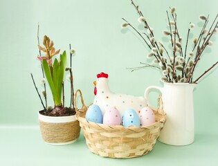 Easter composition, decorative chicken with Easter eggs in a wicker basket on the table and spring...