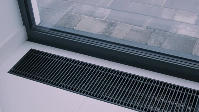 Protective radiator grille built into the floor for heating panoramic windows. Heating grid with ventilation by the floor in hardwood flooring