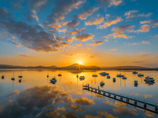 Aerial sunrise waterscape with boats, reflections and low cloud