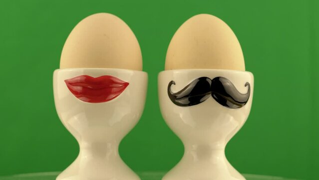 man and woman husband and wife concept shot on a rotating platform in front of a green screen with an egg cup and a boiled egg on it