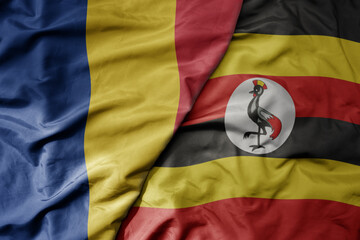 big waving national colorful flag of uganda and national flag of romania .