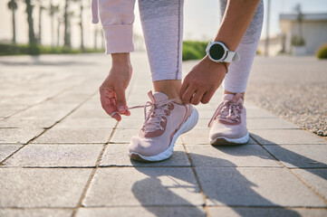 Cropped view of a fitness woman tying shoelaces before training, Getting ready for morning jog...