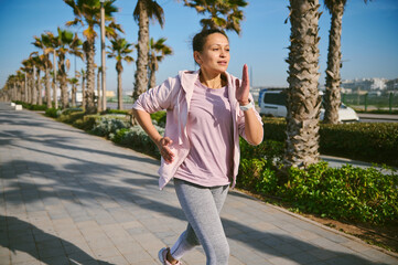 Active woman, runner jogging on the treadmill, enjoying a marathon of Breast Cancer Awareness...