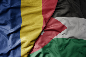 big waving national colorful flag of jordan and national flag of romania .