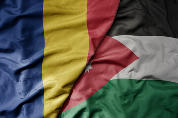 big waving national colorful flag of jordan and national flag of romania .