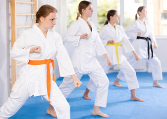 Fototapeta na wymiar In gym, certified woman master coach conducts karate kata lesson with young female students group and shows sequence of actions when conducting close fight
