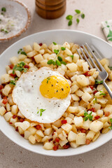 Potato hash with bacon or prosciutto served with fried egg on top