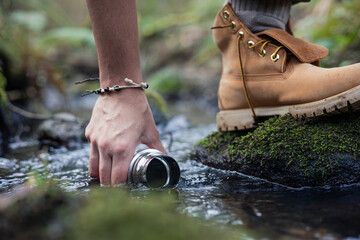 Hand and foot collecting water from river in forest
