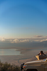 A man holding a binocular looking at Ngorongoro Conservation Area on the rim of the Ngorongoro crater © Dash