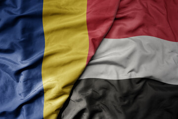 big waving national colorful flag of yemen and national flag of romania .