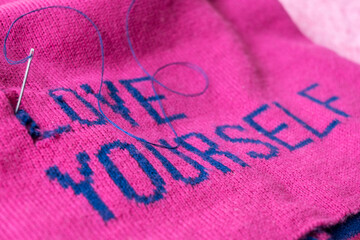 Tailor fixing pink cap with self love message