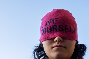 Girl wearing pink cap with self love message in sunny day