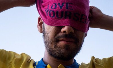 Man wearing pink cap with self love message and taking it off, sunny day