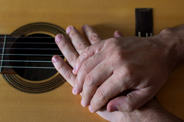 Hands on top of a classical guitar.